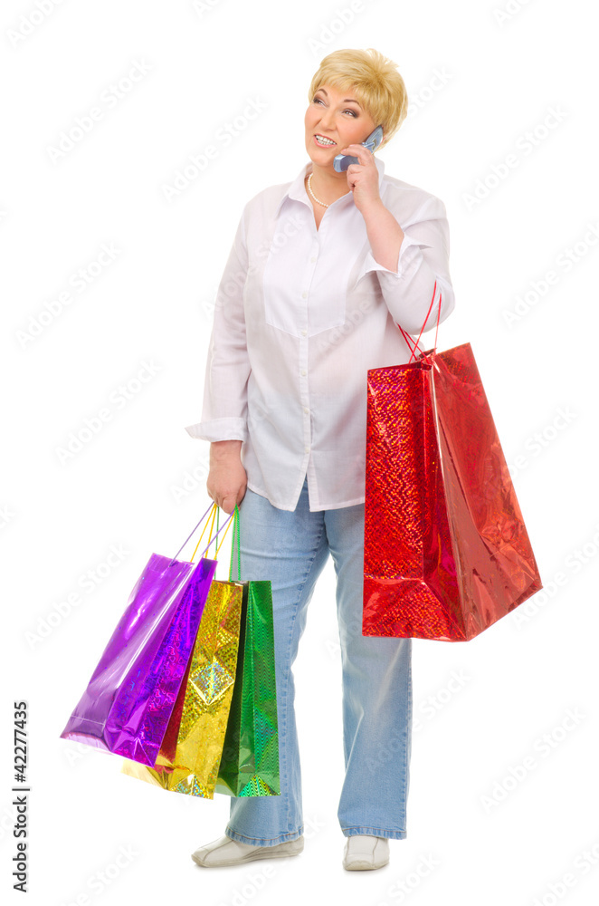 Senior woman with mobile phone and bags