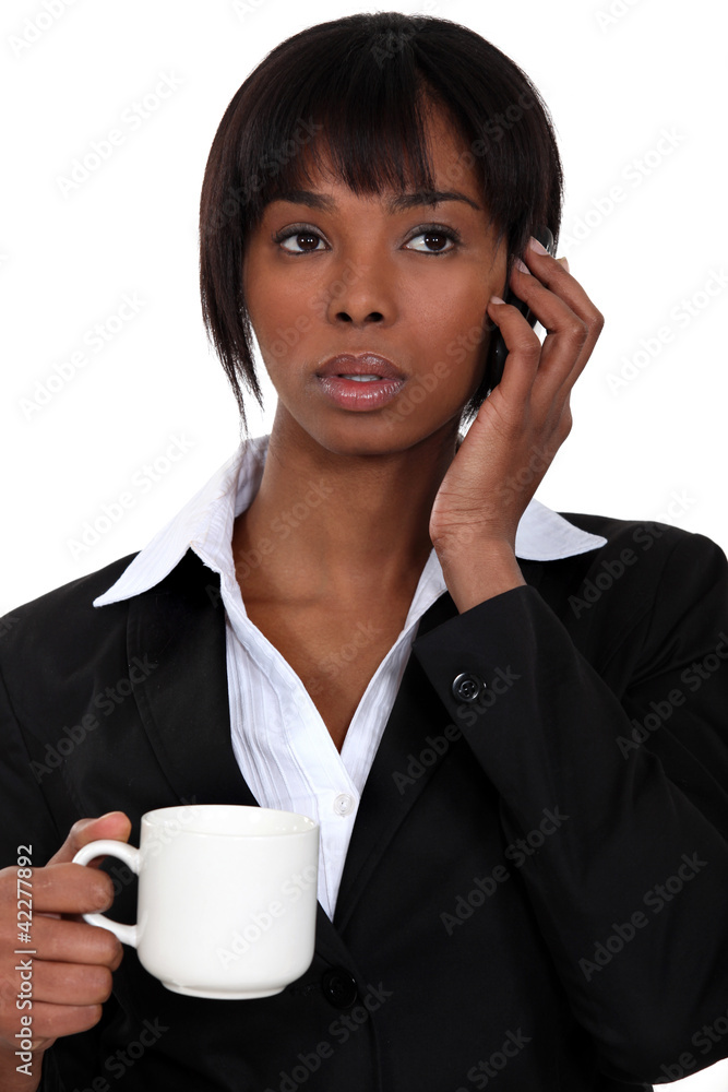 A businesswoman over the phone drinking a coffee. A businesswoman over the phone drinking a coffee.