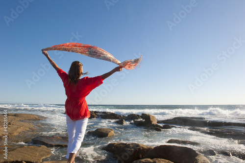 Woman with fabric at windy ocean