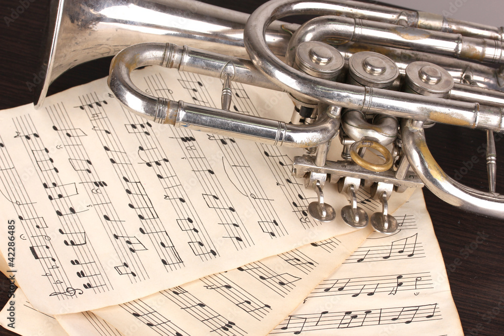 Obraz premium Musical notes and trumpet on wooden table