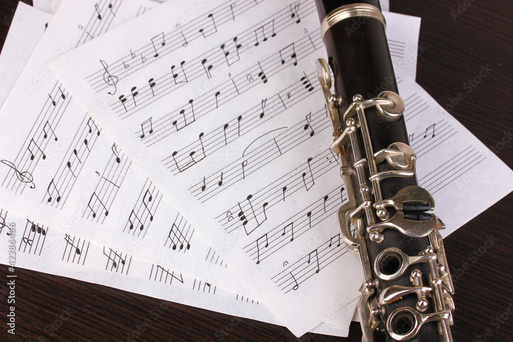 Obraz premium Musical notes and clarinet on wooden table