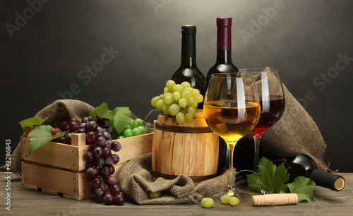 barrel, bottles and glasses of wine and ripe grapes
