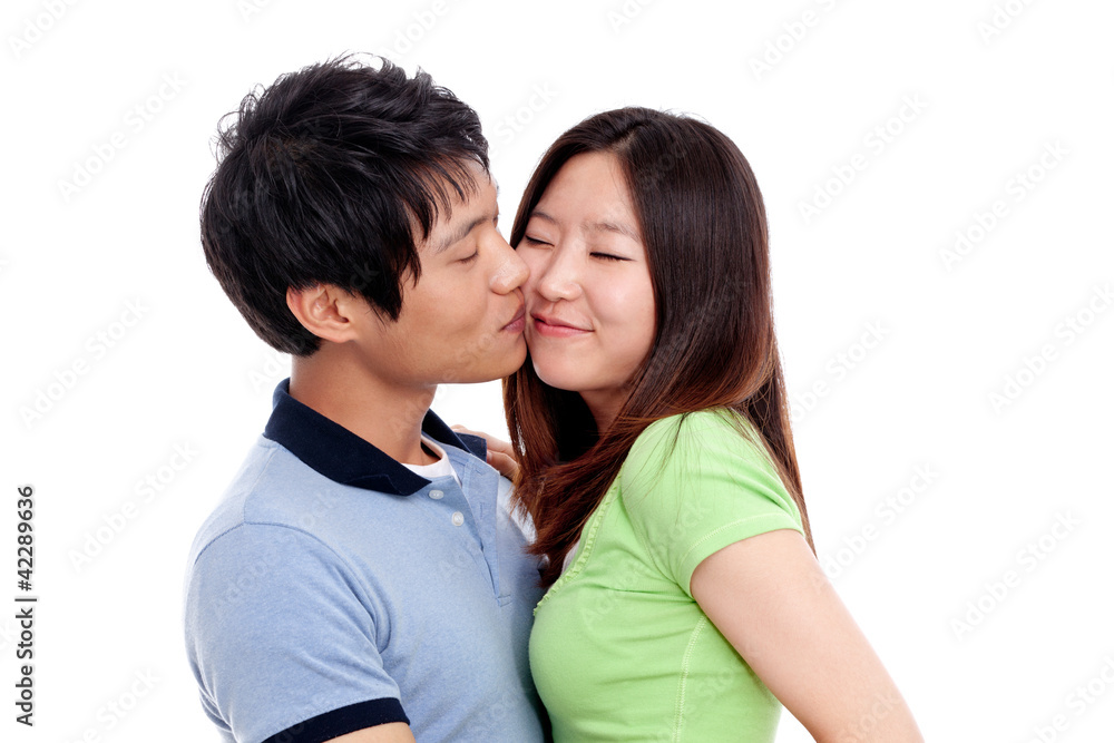 Happy couple hugging and kissing over white background Happy couple hugging and kissing over white background