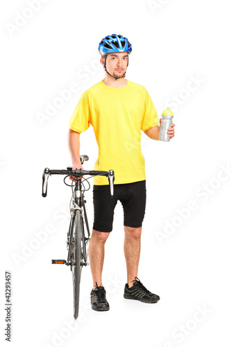 Bicyclist posing next to a bicycle and holding a bottle