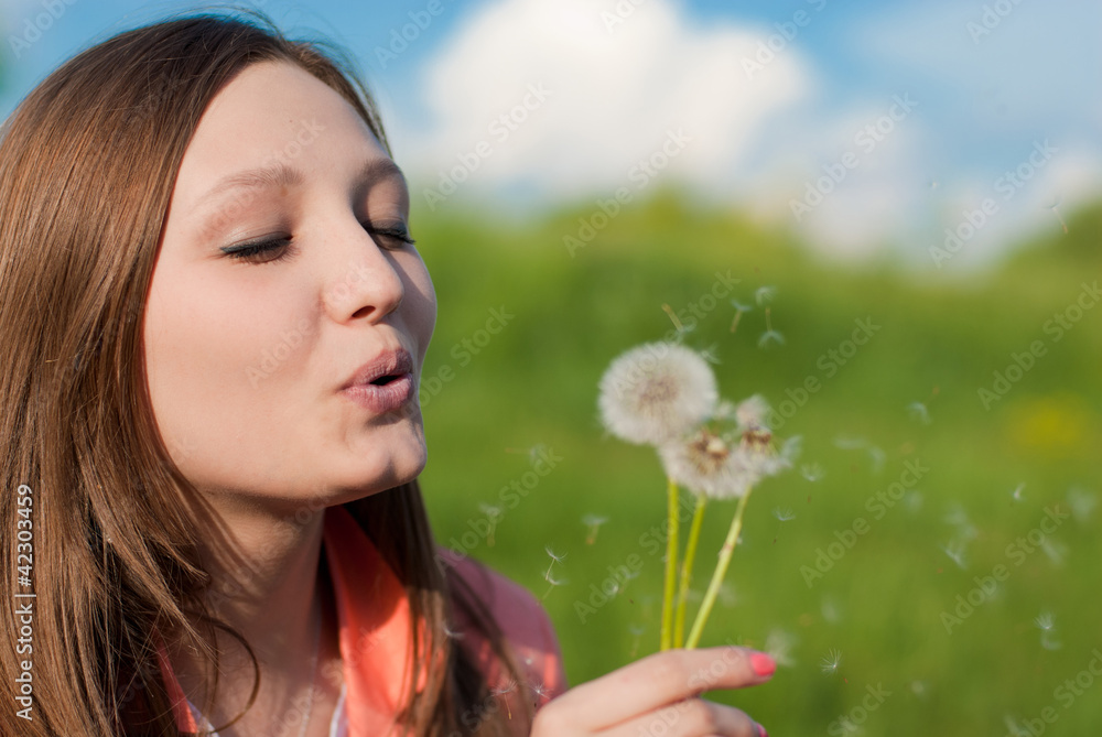 Young woman blowing on dandelion Young woman blowing on dandelion