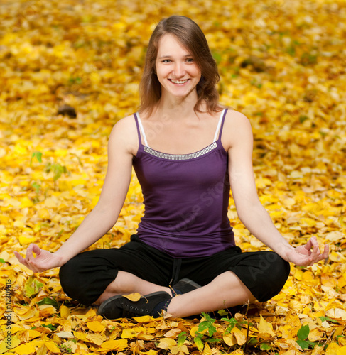 Woman doing yoga exercises in the autumn park