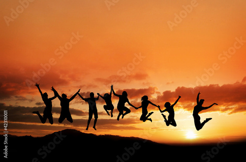 silhouette of teenagers jumping in sunset on mountain range © Alex Koch