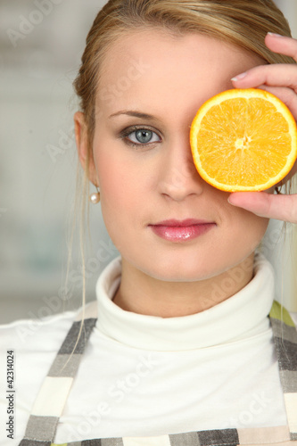 Woman covering her eye with orange slice