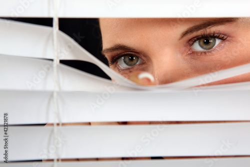 Woman peering through some blinds photo