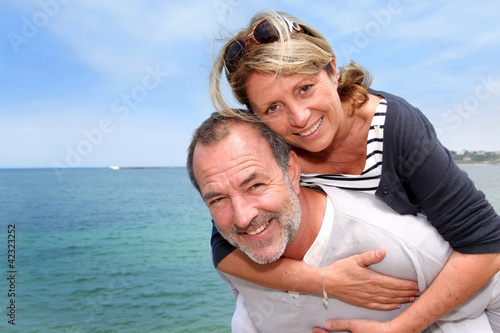 Portrait of senior man holding woman on his back