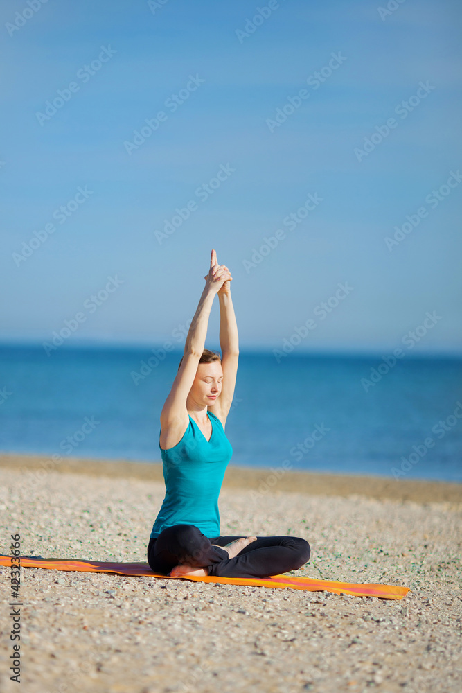 Young woman meditating on the beach . Young woman meditating on the beach .