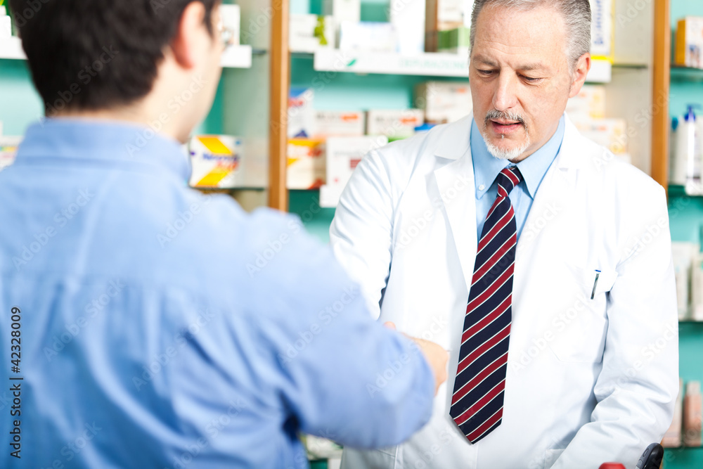 Senior pharmacist dealing with a customer Senior pharmacist dealing with a customer