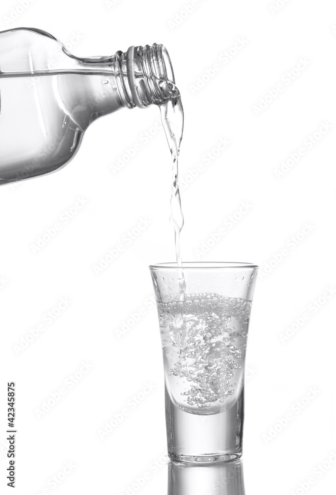 Vodka poured into a glass isolated on white Vodka poured into a glass isolated on white