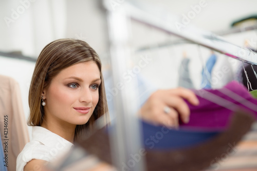 young woman choosing shirt in clothes shop