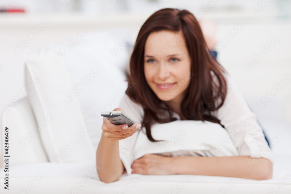 frau mit fernbedienung auf dem sofa frau mit fernbedienung auf dem sofa