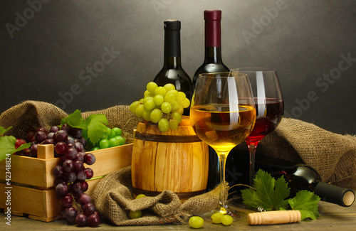 barrel, bottles and glasses of wine and ripe grapes