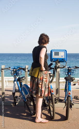tourist looking at bicycle rental machine Nice France