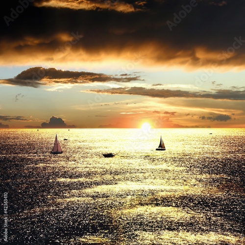Sunset over the sea with sailing boats