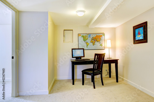 Home office desk with map on the white wall.