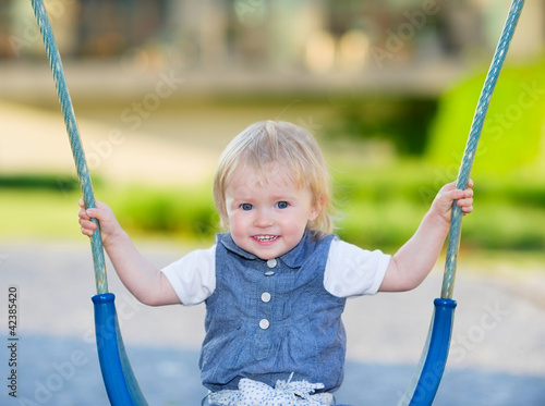 Happy baby sitting on swing photo