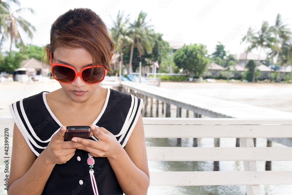Girl with mobile phone sitting at the pier.. Girl with mobile phone sitting at the pier..