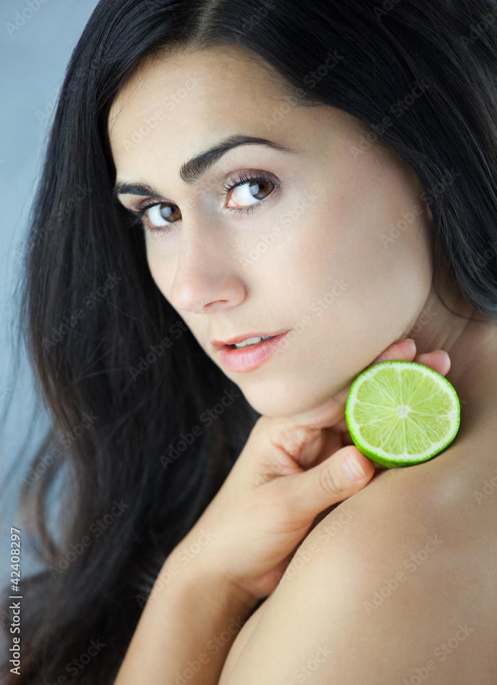 Naklejka premium Piękna dziewczyna trzymająca przekrojoną kwaśna limonkę