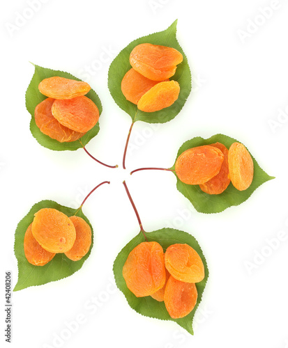delicious dried apricots on green leaves isolated on white