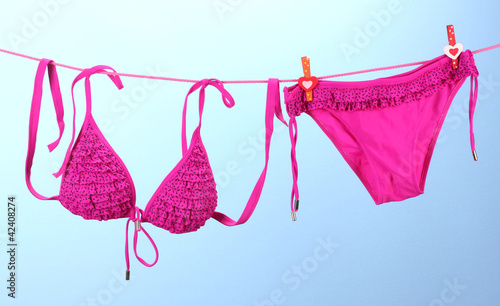 Obraz na płótnie Women's swimsuit hanging on a rope on blue background