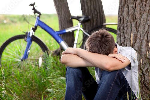 Принти на полотні A teenager with a bicycle in the park on the grass