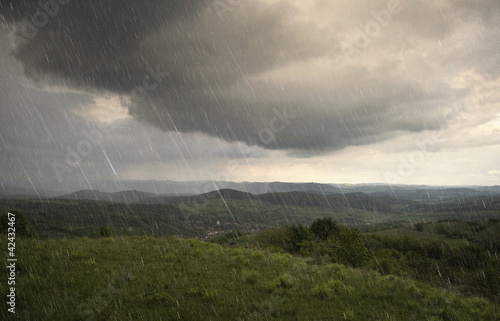 landscape with rain and dramatic clouds over hills