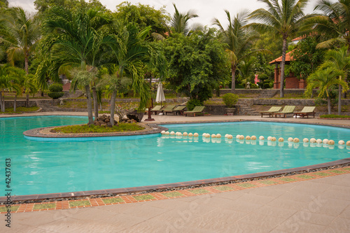 Fototapeta Naklejka Na Ścianę i Meble -  Beach hotel resort swimming pool surrounded by palm trees