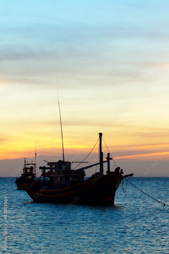 the fishing boat in the sea at a sunset