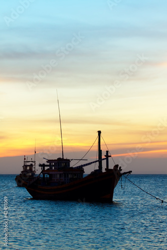 the fishing boat in the sea at a sunset