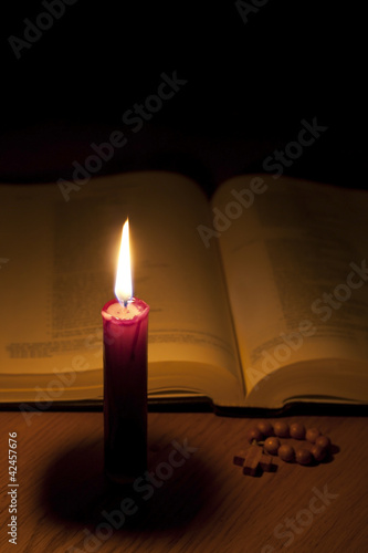 Bible candle and rosary in night background concept