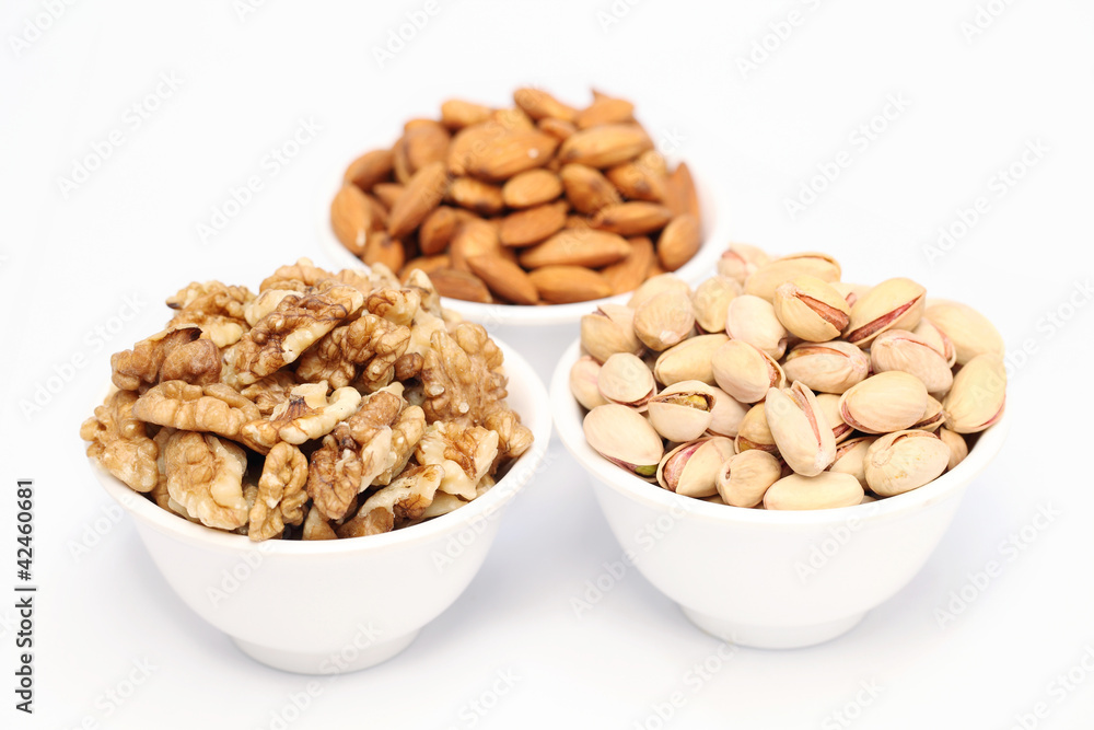 Bowls of almonds,walnuts and pistachios on white background Bowls of almonds,walnuts and pistachios on white background
