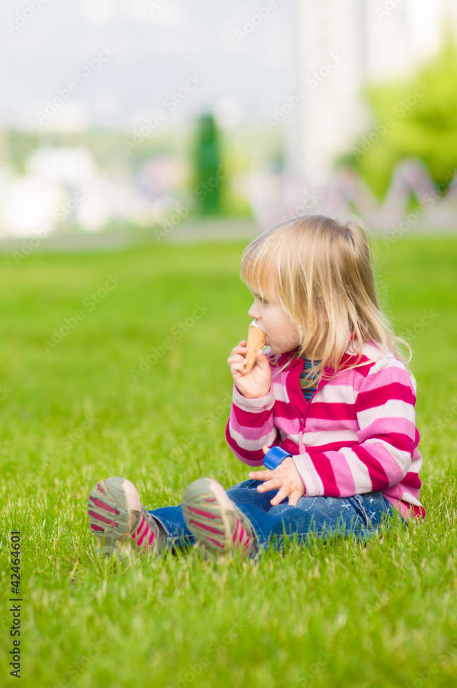 Adorable girl eat ice cream on green grass Adorable girl eat ice cream on green grass