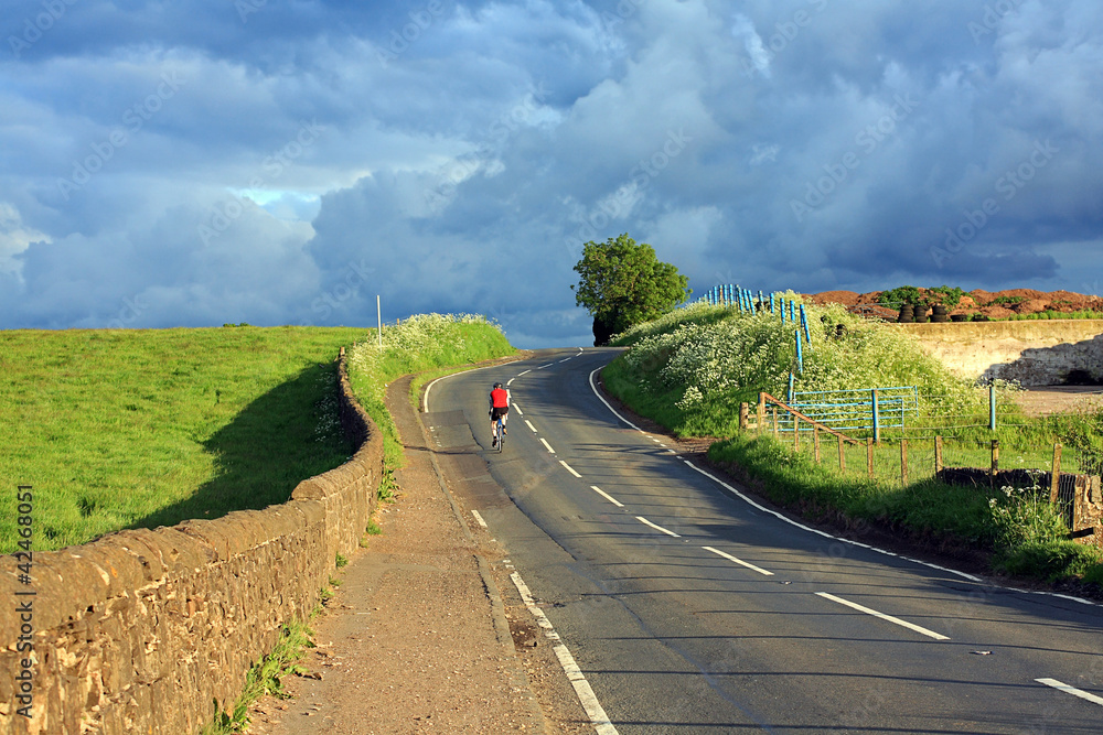 Beautiful Scottish road with a lonely cyclist in the countryside