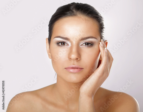 Portrait of young woman with healthy skin touching her face