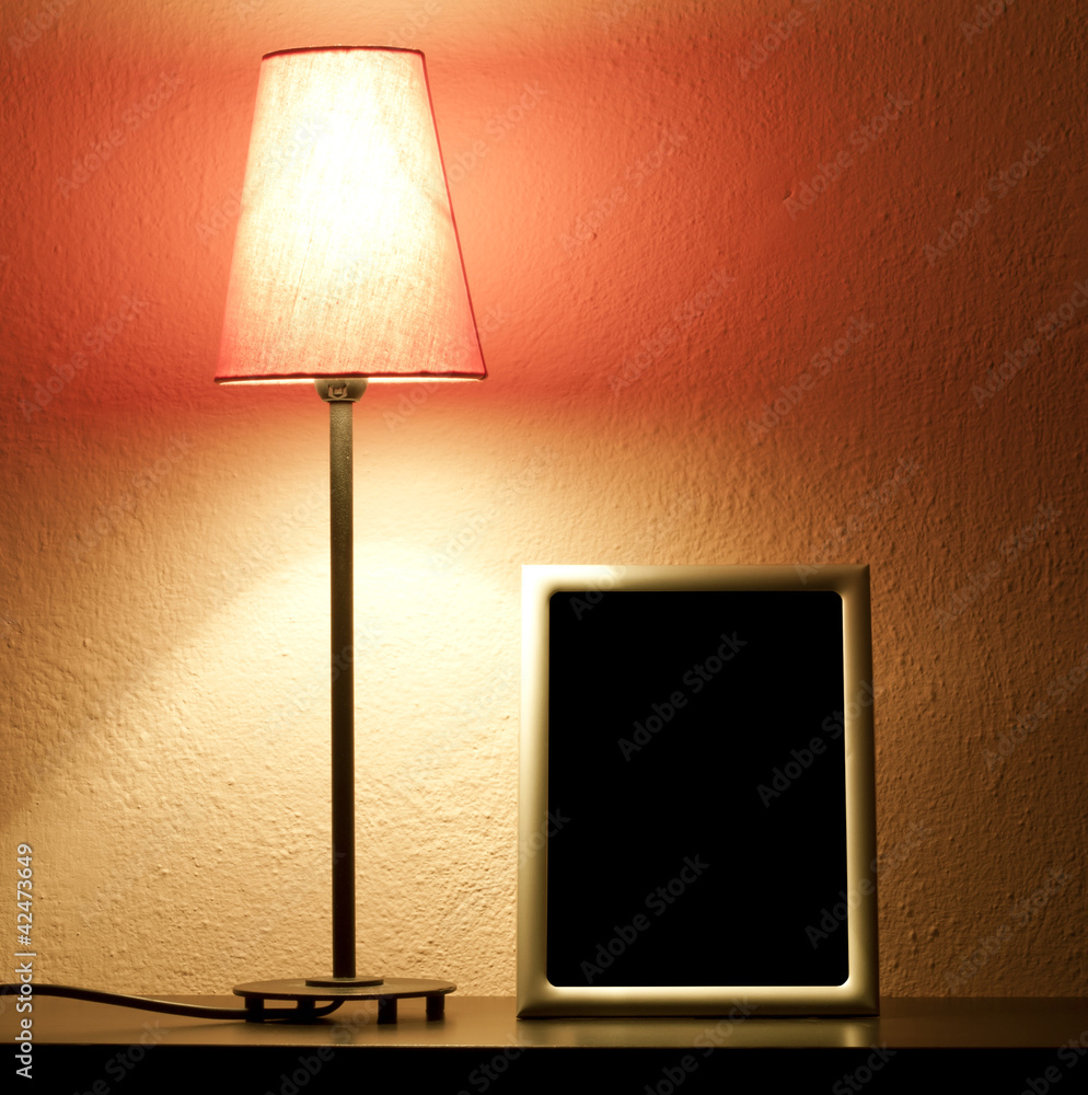 Lamp and empty frame on the shelf in night abstract concept