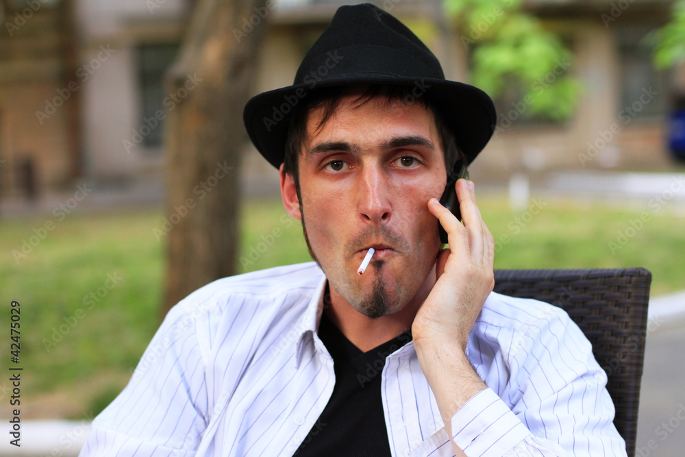Guy is smoking a cigarette and calls on mobile phone Guy is smoking a cigarette and calls on mobile phone