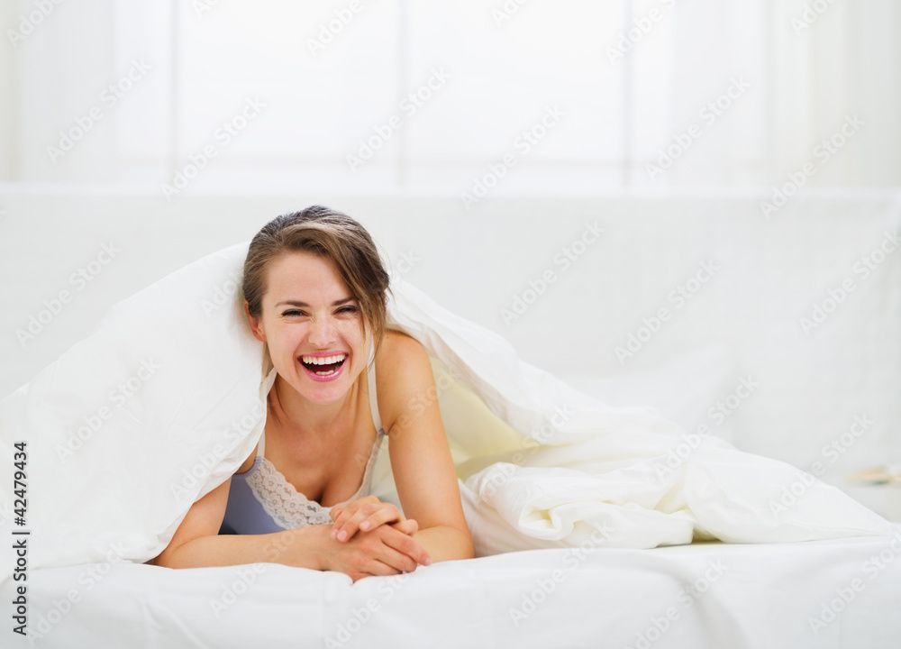 Smiling woman looking out from blanket Smiling woman looking out from blanket