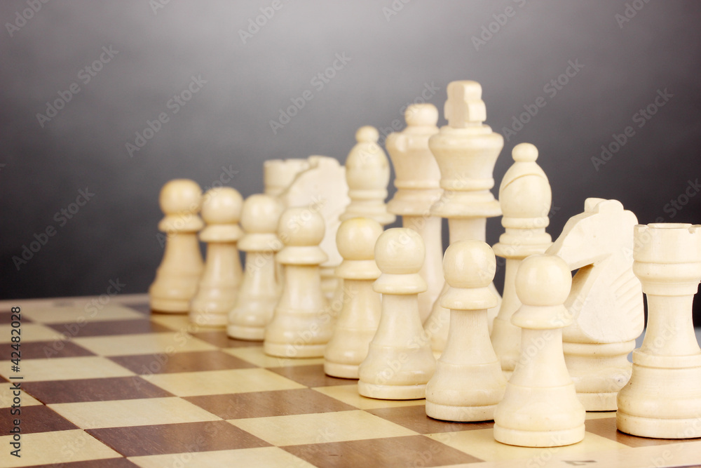 Chess board with chess pieces on grey background