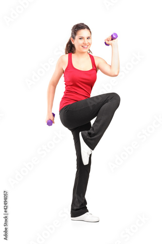 Full length portrait of a smiling teenager lifting up a dumbbell