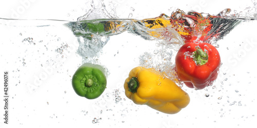 Fototapeta Naklejka Na Ścianę i Meble -  Three peppers falling into water, over white background