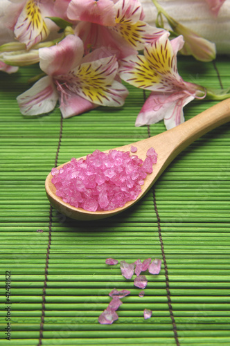bath salt in spoon and orchid flower on green mat