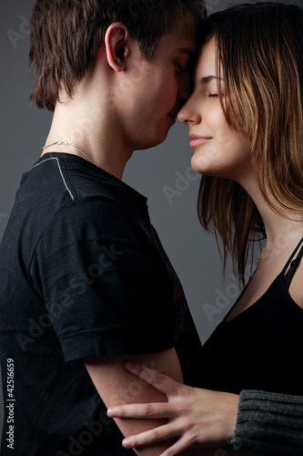 Young couple standing together against a grey wall