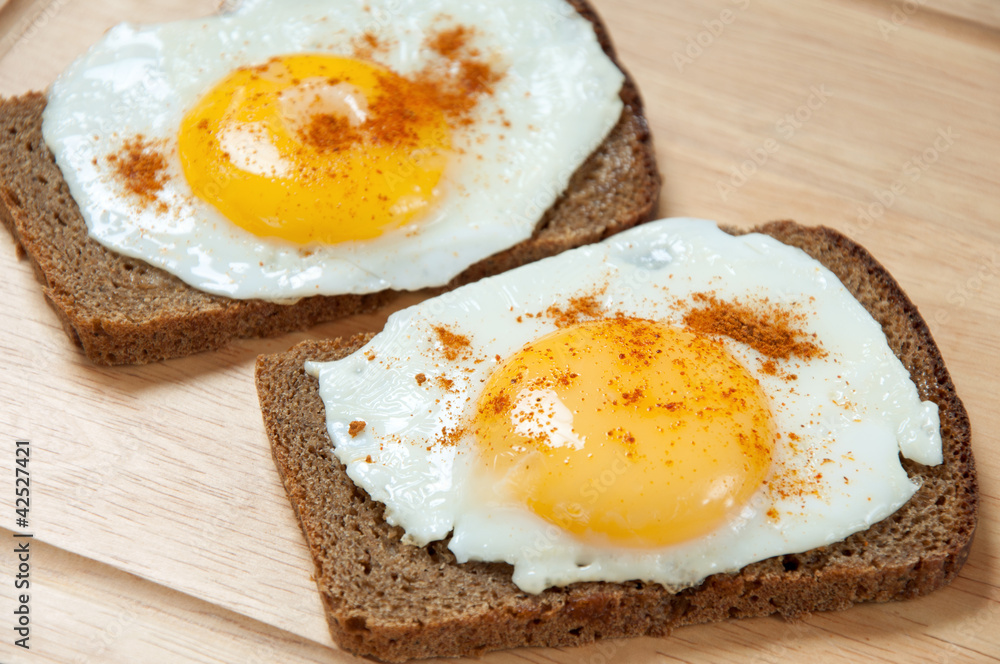 Close-up of two toasts with fried eggs, studio shot Close-up of two toasts with fried eggs, studio shot