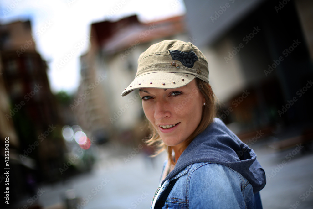Cheerful woman wearing blue jeans jacket and hat in town