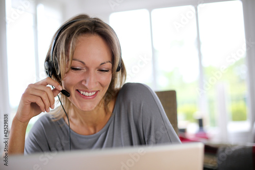 Portrait of woman with headset in front of laptop