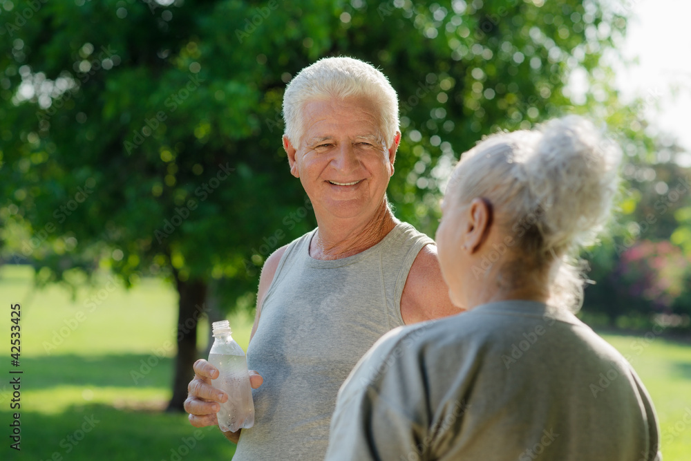 Seniors drinking water after fitness in park Seniors drinking water after fitness in park